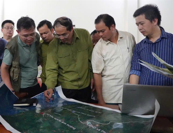 A group of men looking at a mapDescription automatically generated